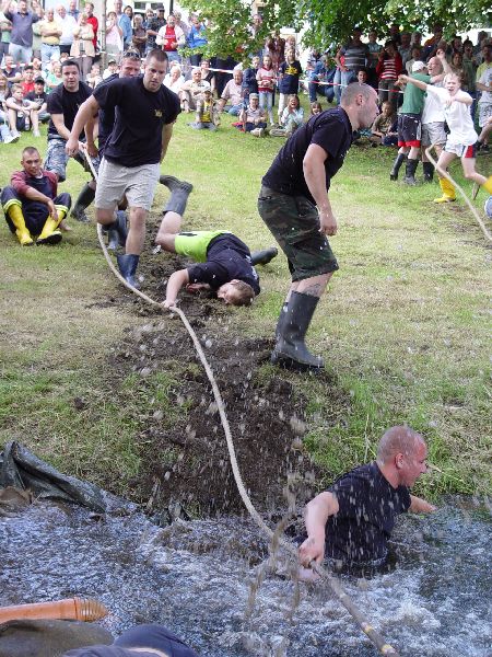 Männer ziehen mit Seilen an einem schlammigen Erdhaufen