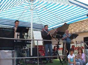 Musikband spielt live unter einem blau-weißen Streifendach