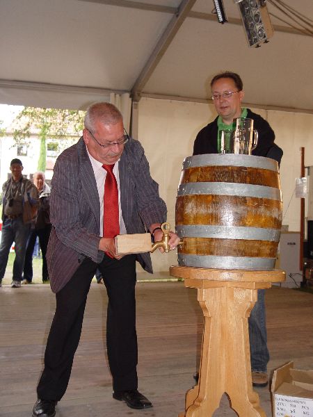 Mann öffnet Weinfass mit Zeremonialhammer