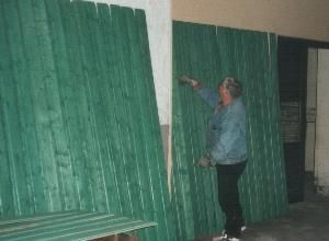 Mitarbeiterin bemalt grüne Holzpaneele