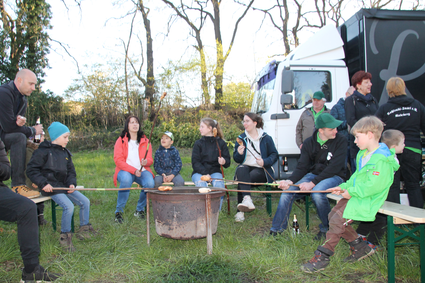 Familie und Kinder braten Würstchen am offenen Feuer