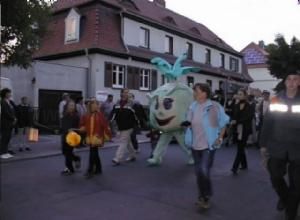 Personen in Kostümen bei einem Umzug, darunter ein Kohlrabi-Kostüm