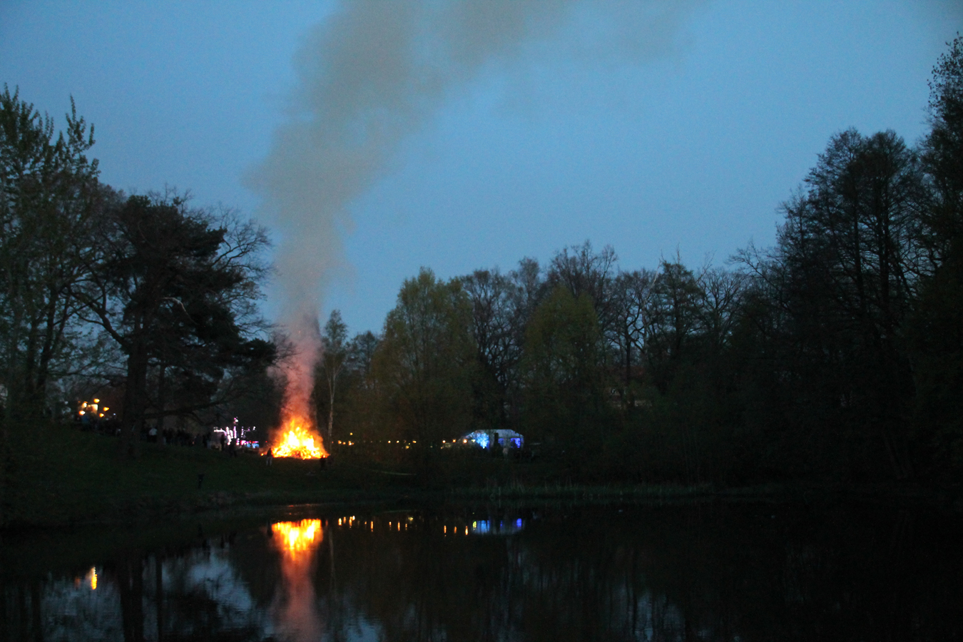 Kirmesfeuer spiegelt sich im Wasser bei Dämmerung