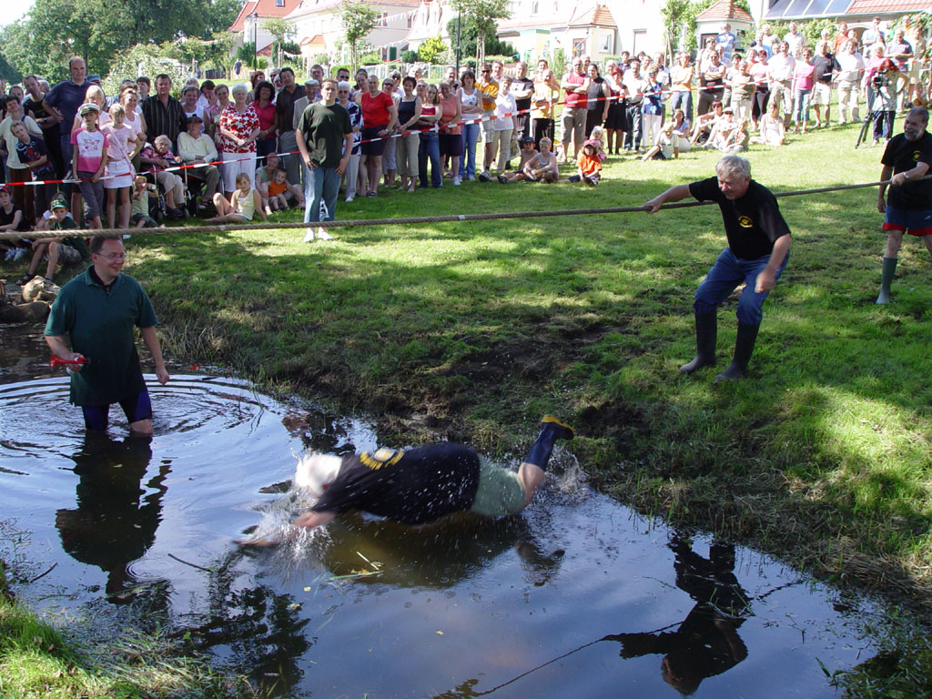 Verlierer eines Taukampfes fallen im Schlamm in den Graben