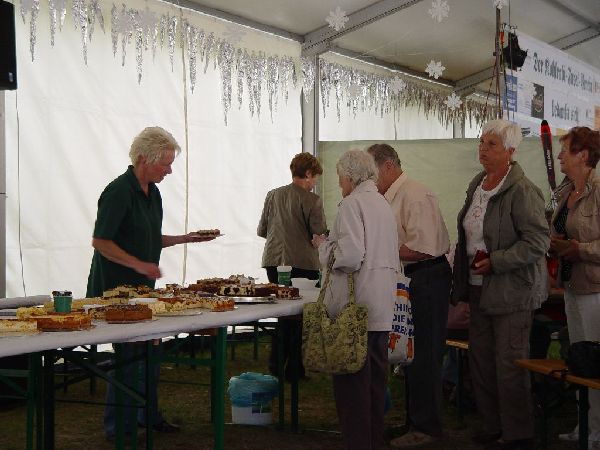 Ältere Menschen beim Kuchenverkauf unter einem Festzelt